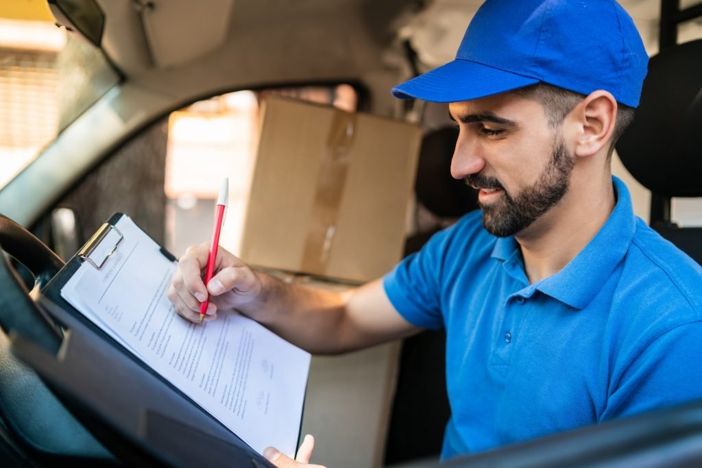 Delivery man checking delivery list in van.