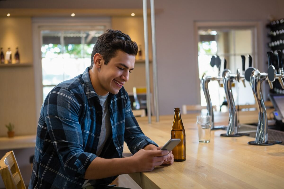 Smiling man using phone at bar